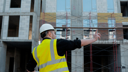 The construction manager is pointing towards a section of the building 