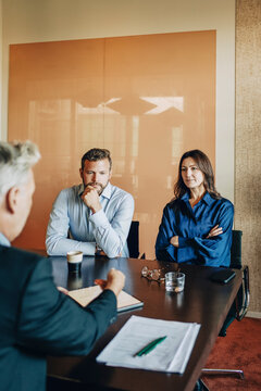Couple sitting with male lawyer explaining agreement rules while sitting in office