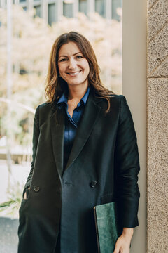 Portrait of smiling female lawyer standing with hand in pocket