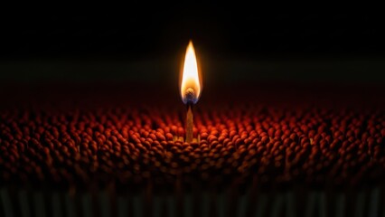 Single candle flame burning brightly in the darkness illuminating a textured surface