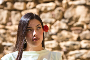 A beautiful Spanish teenager with long dark hair and a delicate, beautiful red poppy in her hair...