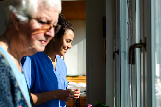 Smiling female nursing assistant spending leisure time with elderly woman at home
