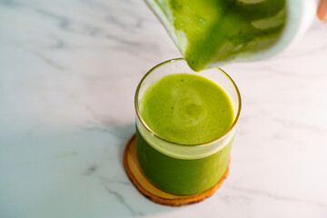 Pouring freshly prepared matcha into a glass for a smooth green tea drink.