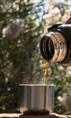 Close-Up of Hand Pouring Hot Coffee from Green Thermos Outdoors