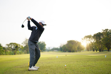 Golfer performing a powerful tee off swing on bright scenic fairway.