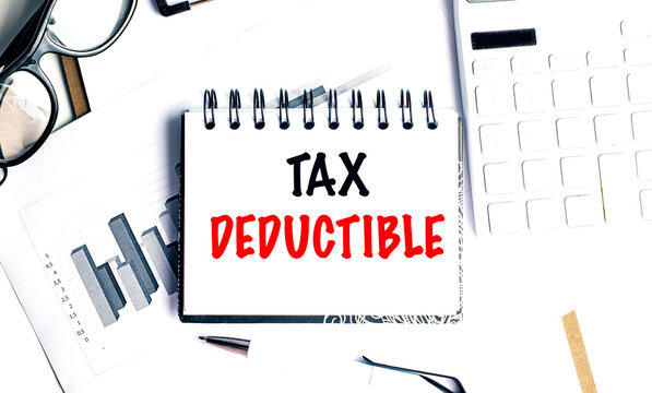 Tax deductible phrase on spiral notebook with financial documents, calculator, pen and glasses