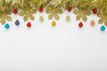 Beautiful shiny golden tinsel, snowflakes and colorful baubles on light gray table background....