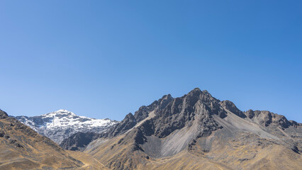 Fototapeta premium Picturesque high-altitude landscape. Snow-capped and vegetation-free peaks against a clear blue sky. Copy space. Peru 