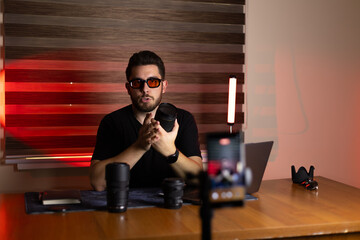 A man is preparing to record a video blog at his desk with recording equipment