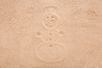 Drawn snowman shape with snowflakes on dry light brown sea sand background. Closeup. Top down view.