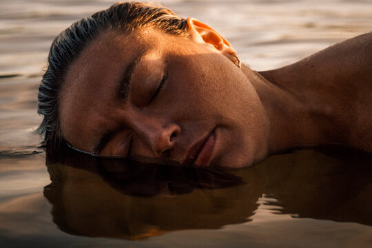 Carefree woman embracing water with eyes closed in lake