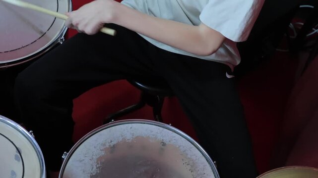 Boy playing drums with drumsticks