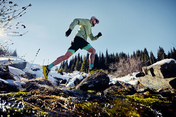 Man running trough the river in the winter mountains