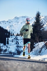 Man running on the road in the winter mountains