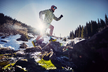 Man running trough the river in the winter mountains
