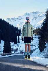 Man running on the road in the winter mountains