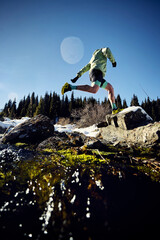 Man running trough the river in the winter mountains