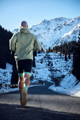 Man running on the road in the winter mountains