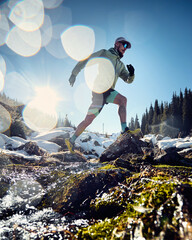 Man running trough the river in the winter mountains