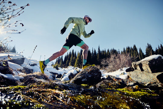 Man running trough the river in the winter mountains