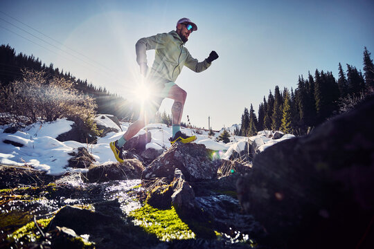 Man running trough the river in the winter mountains