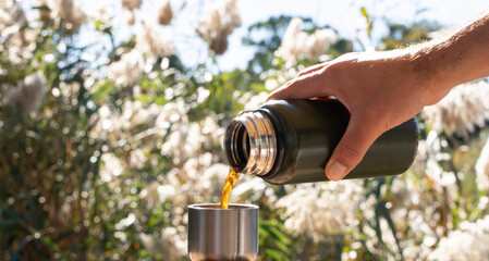 Close-Up of Hand Pouring Hot Coffee from Green Thermos Outdoors