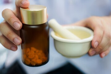 Pharmacist Holding Mortar and Amber Bottle During Medication Preparation