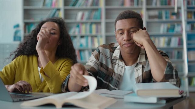 Bored ethnic students studying burnout in library laptop project homework tired African American man Latino Arabian woman classmates struggling teamwork difficult exam preparing female male university