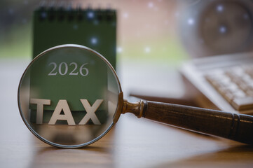 2026 tax concept with magnifying glass highlighting TAX on a green calendar, symbolizing financial review, tax analysis, accounting, deadlines, and fiscal planning