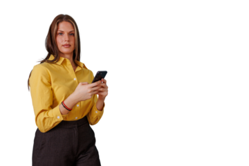 Professional woman in yellow shirt using smartphone, standing confidently and looking at camera, transparent background