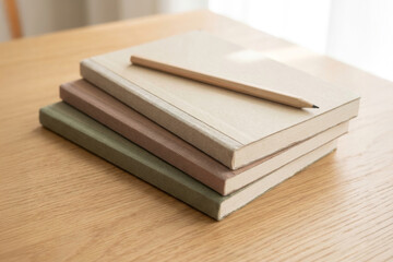 Stack of notebooks and pencil on wooden table