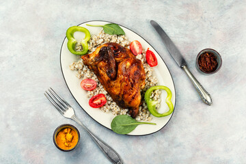 Half grilled chicken on the grill served with porridge.
