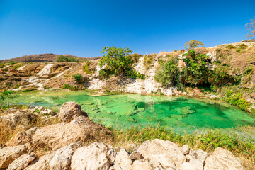 Wadi Darbat natural park in Dhofar, Oman, presenting clear emerald water with waterfalls cascading...