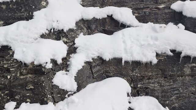 Neve e ghiaccioli sulla parete di roccia