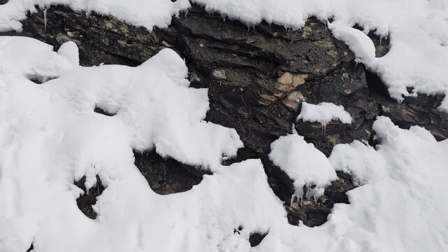 Neve e ghiaccioli sulla parete di roccia