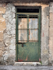 old rusty green door against stone wall on abandoned house entrance  