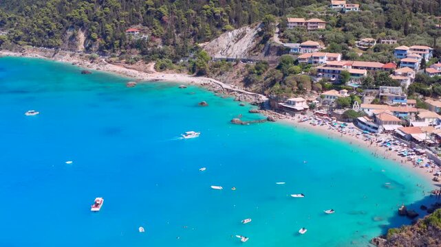 Greece typical charming village and beach at blue sea on Greek island. Tourists swimming and small boats in vacation paradise destination Paralia Agios Nikitas Lefkada
