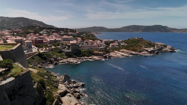 Cinematic Aerial Drone Flyover Reveals the Dramatic Rocky Coastline and Historic Citadel of Calvi, Haute-Corse, Corsica, France.