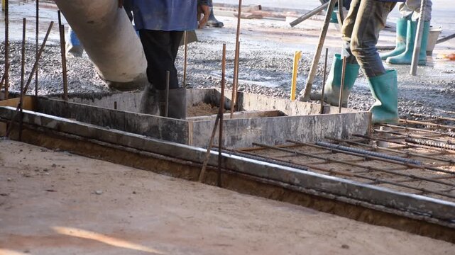 Construction workers pour concrete floors, Concrete pouring during commercial floor construction faceless workers coordinating defocused, Construction workers pouring concrete over metal grid with cem