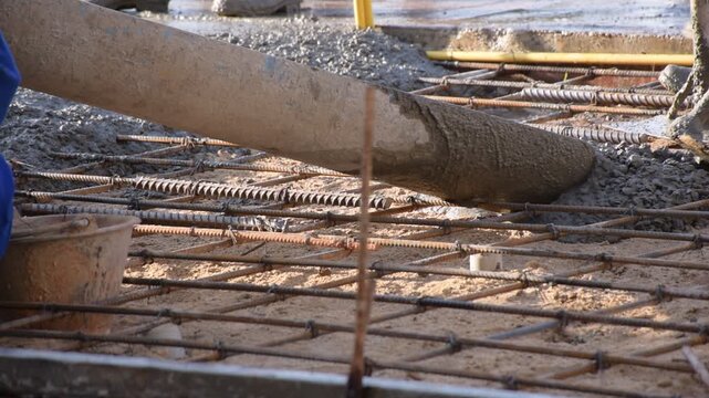 Construction workers pour concrete floors, Concrete pouring during commercial floor construction faceless workers coordinating defocused, Construction workers pouring concrete over metal grid with cem