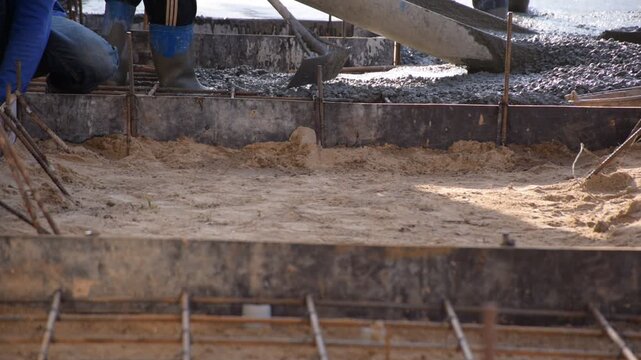 Construction workers pour concrete floors, Concrete pouring during commercial floor construction faceless workers coordinating defocused, Construction workers pouring concrete over metal grid with cem