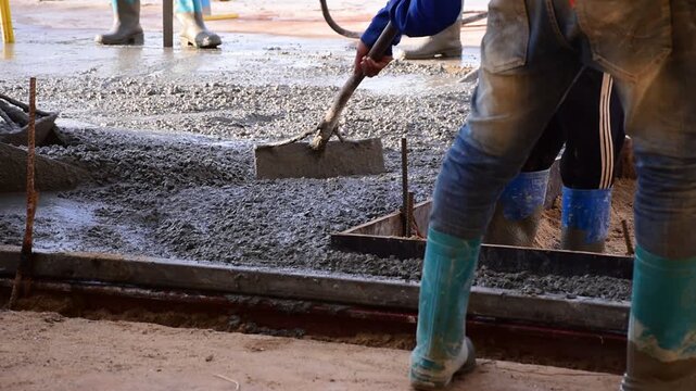 Construction workers pour concrete floors, Concrete pouring during commercial floor construction faceless workers coordinating defocused, Construction workers pouring concrete over metal grid with cem