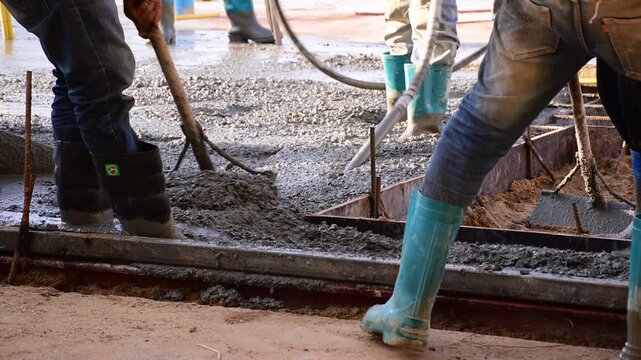 Construction workers pour concrete floors, Concrete pouring during commercial floor construction faceless workers coordinating defocused, Construction workers pouring concrete over metal grid with cem