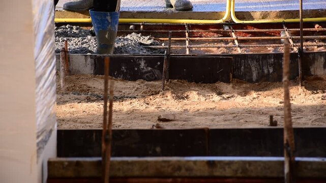 Construction workers pour concrete floors, Concrete pouring during commercial floor construction faceless workers coordinating defocused, Construction workers pouring concrete over metal grid with cem