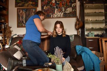 Mother bonding her young adult daughter's hair at home