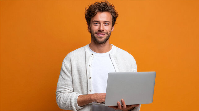 Portrait of a smiling young man working on laptop against orange background. - Powered by Adobe