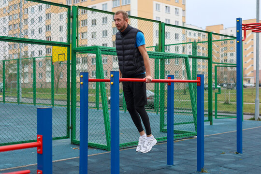 Street workout Man doing dips on parallel bars at outdoor gym