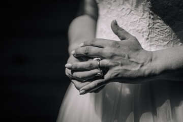 Elegant hands of a bride adorned with a wedding ring, showcasing delicate fingers and intricate...