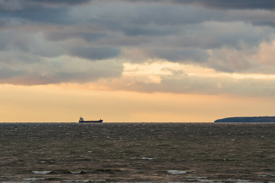 Cargo ship sailing on the rough Baltic Sea horizon near Aegna island under a dramatic cloudy sunset sky in Estonia.