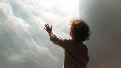 Child reaches toward luminous cloudy sky